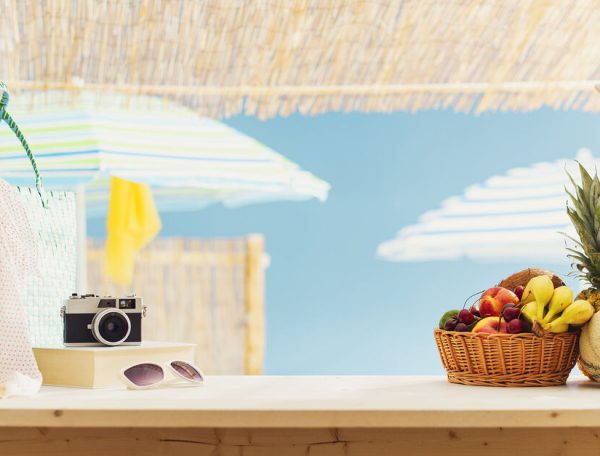 Fresh fruit, bags and camera on the beach bar kiosk, summer and tourism concept